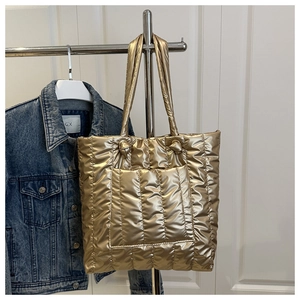 Detail of metallic gold quilted tote bag showing vertical stitching and soft padded texture