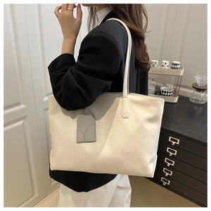 Detail of creamy white leather tote bag with subtle texture and detachable luggage tag
