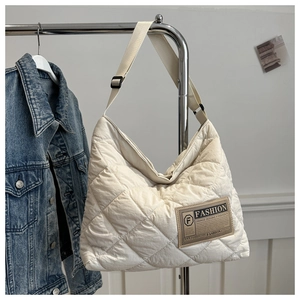 Détail du sac fourre-tout matelassé crème avec coutures en losange et bandoulière réglable