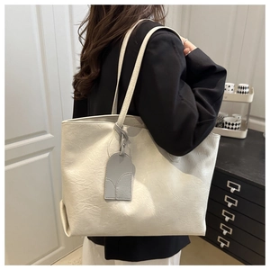 Detailed texture of off-white tote bag with natural pleats and grey arc charm