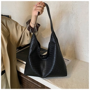 Detail shot of the woven texture and wide shoulder strap on the black bucket bag