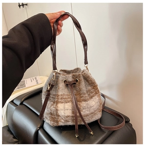 Detalle de bolso cubo de felpa a cuadros con cordón de cuero y asa trenzada