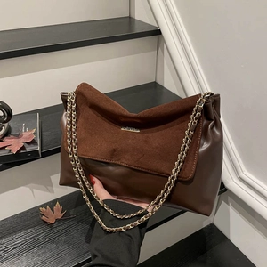 Brown leather shoulder bag with gold chain strap on autumn-themed stairs