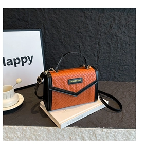 Detail view of the orange and black woven texture handbag with a metallic logo plate