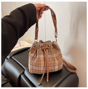 Detalle del bolso tipo saco de lana a cuadros con cordón de cuero y herrajes dorados
