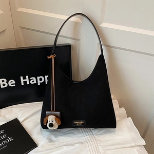 Sac hobo noir en daim avec pendentif chiot en peluche sur fond de tissu blanc élégant