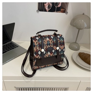 Detail of vintage geometric plaid backpack with brown leather trim on a white desk