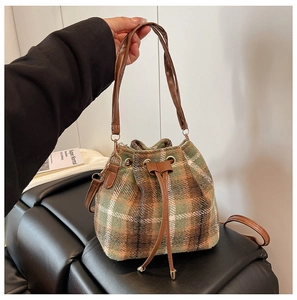 Detalle de bolso cubo de cuadros con textura de tweed y cierre de cordón de cuero