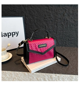 Detailed view of fuchsia woven handbag with gold hardware and black handle straps