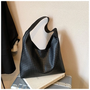 Macro detail of the premium Intrecciato woven texture and leather strap on the black tote