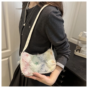 Detail of denim crossbody bag featuring frayed edges and colorful star patterns