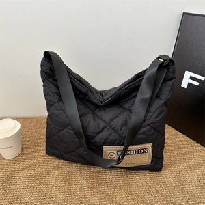 Chic black quilted tote bag for women with fashion label and wide shoulder straps