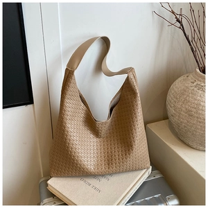 Detail of a brown woven texture hobo tote bag placed on vintage books and suitcase