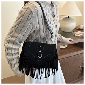 Close-up of vintage black fringe saddle bag with metallic ring and suede texture