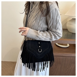 Detail of vintage black matte saddle bag featuring long tassels and metal D-ring hardware