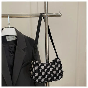 Détail du sac hobo en tweed à damier avec bords effilochés sur support d'étalage