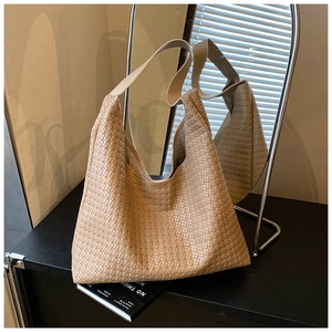 Close-up of beige woven tote bag texture with detailed cross-knit hobo shoulder design