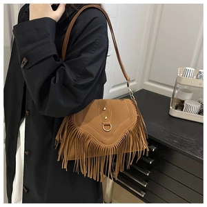 Detail of brown fringe shoulder bag with metallic ring and stud accents on suede texture