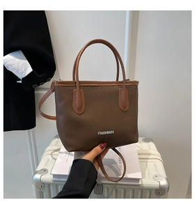 Close-up of brown litchi pattern leather tote bag with silver FASHION metallic logo