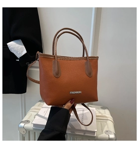 Close-up of orange pebble leather tote bag with silver FASHION logo and shoulder strap