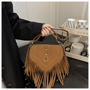 Close-up of brown suede saddle bag featuring long tassels and gold metal buckle