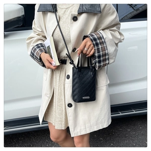 Détail du mini sac cabas tressé noir avec logo métallique et bandoulière en cuir chic
