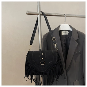 Close-up of black fringe saddle bag with golden metal ring and V-shaped flap cover