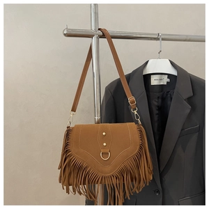 Detail of vintage brown suede saddle bag with metal studs and decorative long tassels