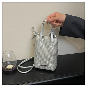 Detailed view of silver woven leather crossbody phone bag with knot strap and metal tag