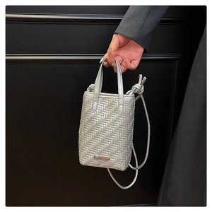 Macro view of silver woven texture and metallic bar detail on this chic square handbag