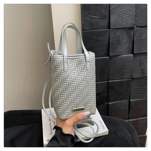 Detail of silver woven handbag with round handles and metal logo plate on the base