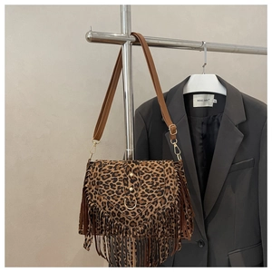 Detail of leopard print crossbody bag with dense fringe accents and brown strap