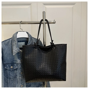 Detail shot of black woven leather tote bag with premium cross-braided craft texture