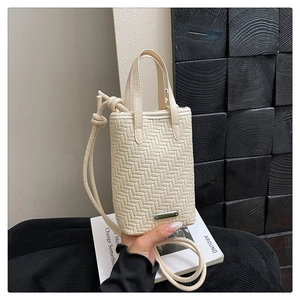Close-up of cream woven phone bag showing fine leather texture and metal logo plate
