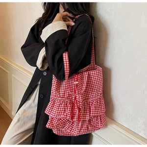 Detail view of red gingham tote bag featuring double layer ruffles and drawstring closure