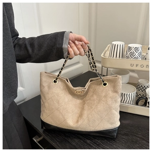 Detail of beige quilted tote bag with gold chain strap and elegant metallic twist lock