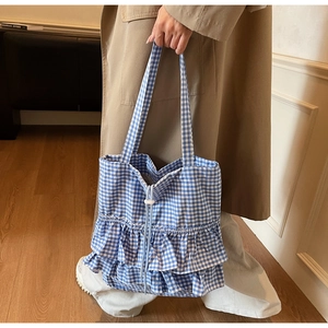 Detail of gingham tote bag featuring layered ruffle edges and a white drawstring closure