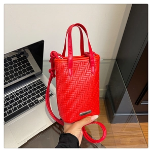 Detail of red woven leather mini bag with thick rope strap and metal logo plate