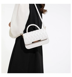 Detalle del bolso bandolera acolchado blanco con cierre dorado y costuras en V