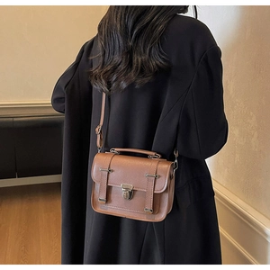 Rear view of a model wearing a vintage brown crossbody square bag with metal buckle and strap