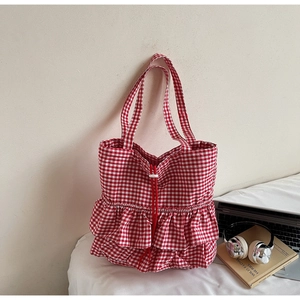 Dettaglio della borsa tote a quadretti rossi con volant decorativi e chiusura a coulisse