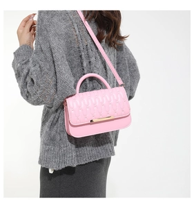 Detalle de bolso bandolera rosa acolchado con adorno dorado sobre el hombro