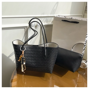 Detail of black woven tote bag with bohemian beaded charm and matching inner pouch