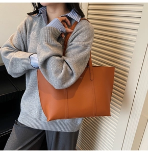 Sac fourre-tout en cuir marron porté par un mannequin dans un style chic urbain