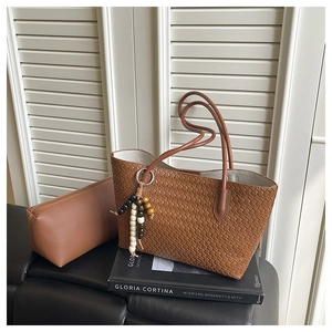 Close-up of brown woven tote bag with matching zippered pouch and beaded pendant detail