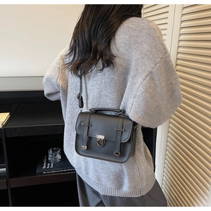 Detail of black pebbled leather messenger bag with matte silver hardware and top handle