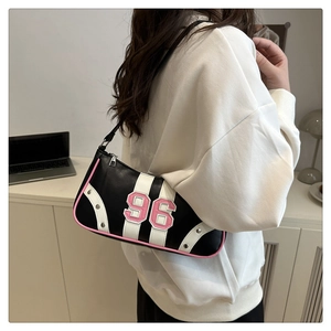 Dettaglio borsa Boston nera con numeri 96 rosa e rivetti argento su felpa bianca