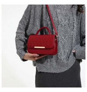 Detalle de bolso acolchado rojo con cierre de metal dorado y asa superior elegante