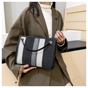 Detail of a chic tri-color woven tote bag featuring vertical stripes and gold chain strap