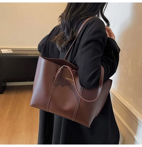 Détail d'un grand sac cabas marron en cuir avec lettrage doré pour le trajet quotidien